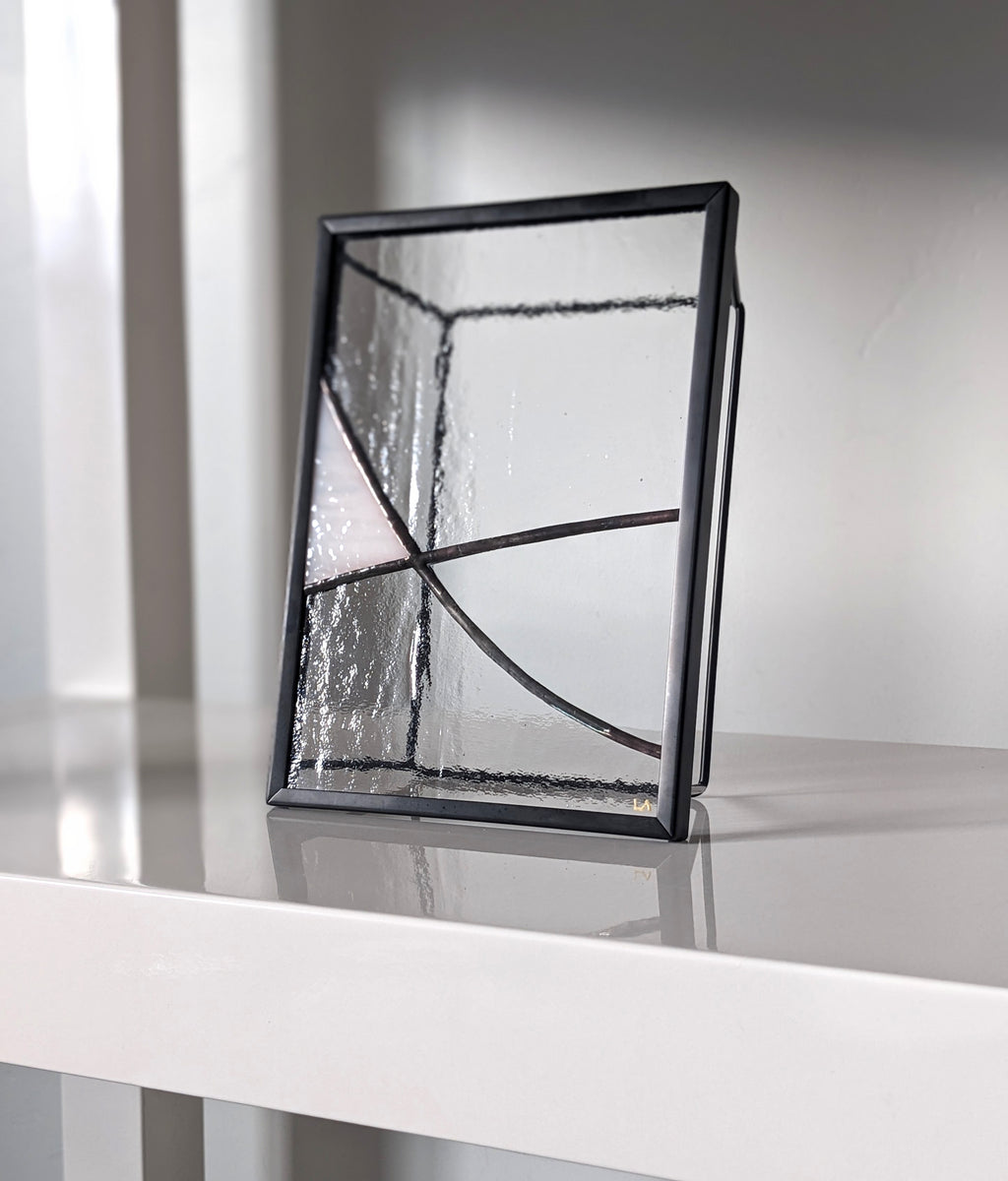 Decorative glass piece with black frame on a white surface