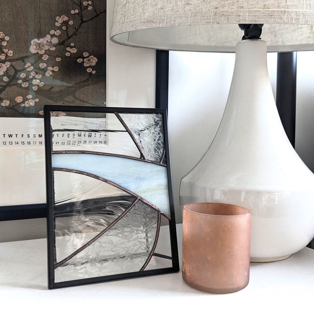 Decorative items including framed glass artwork, a white lamp, and a copper cup on a surface.