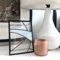 Decorative items including framed glass artwork, a white lamp, and a copper cup on a surface.