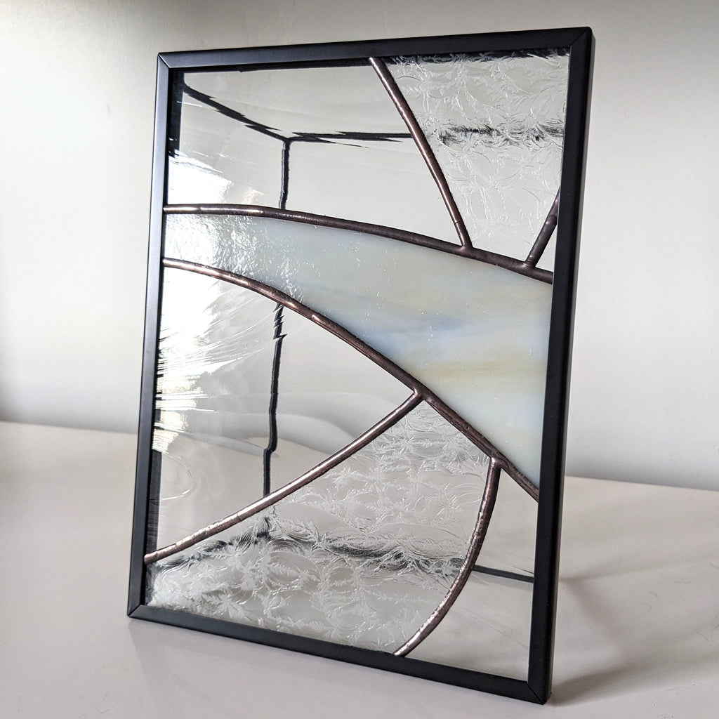 Framed glass artwork on a white surface with a neutral background.