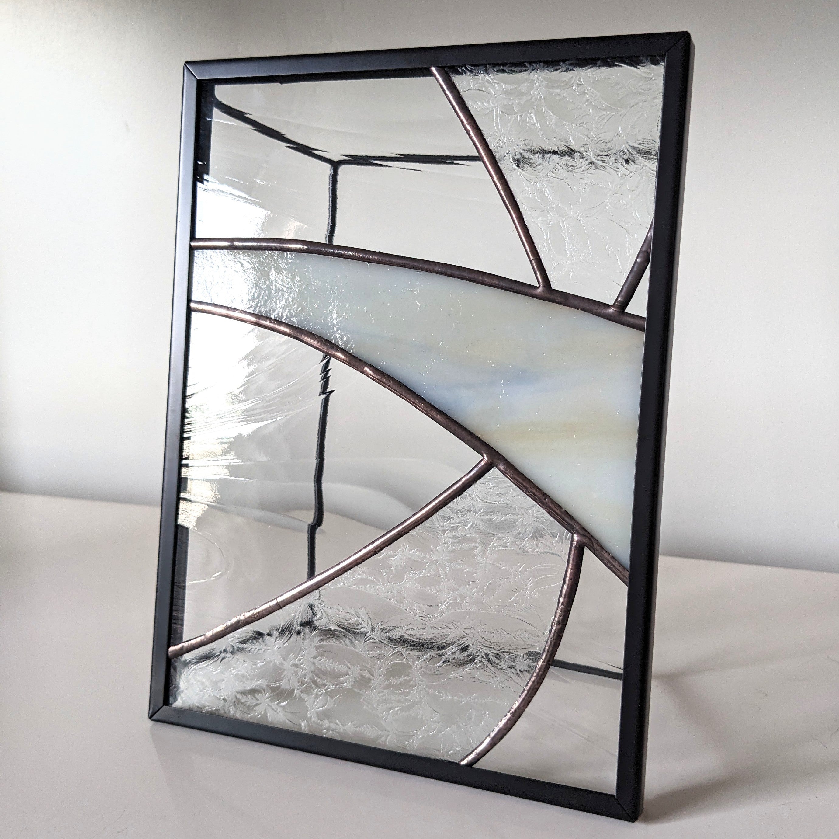 Framed glass artwork on a white surface with a neutral background.